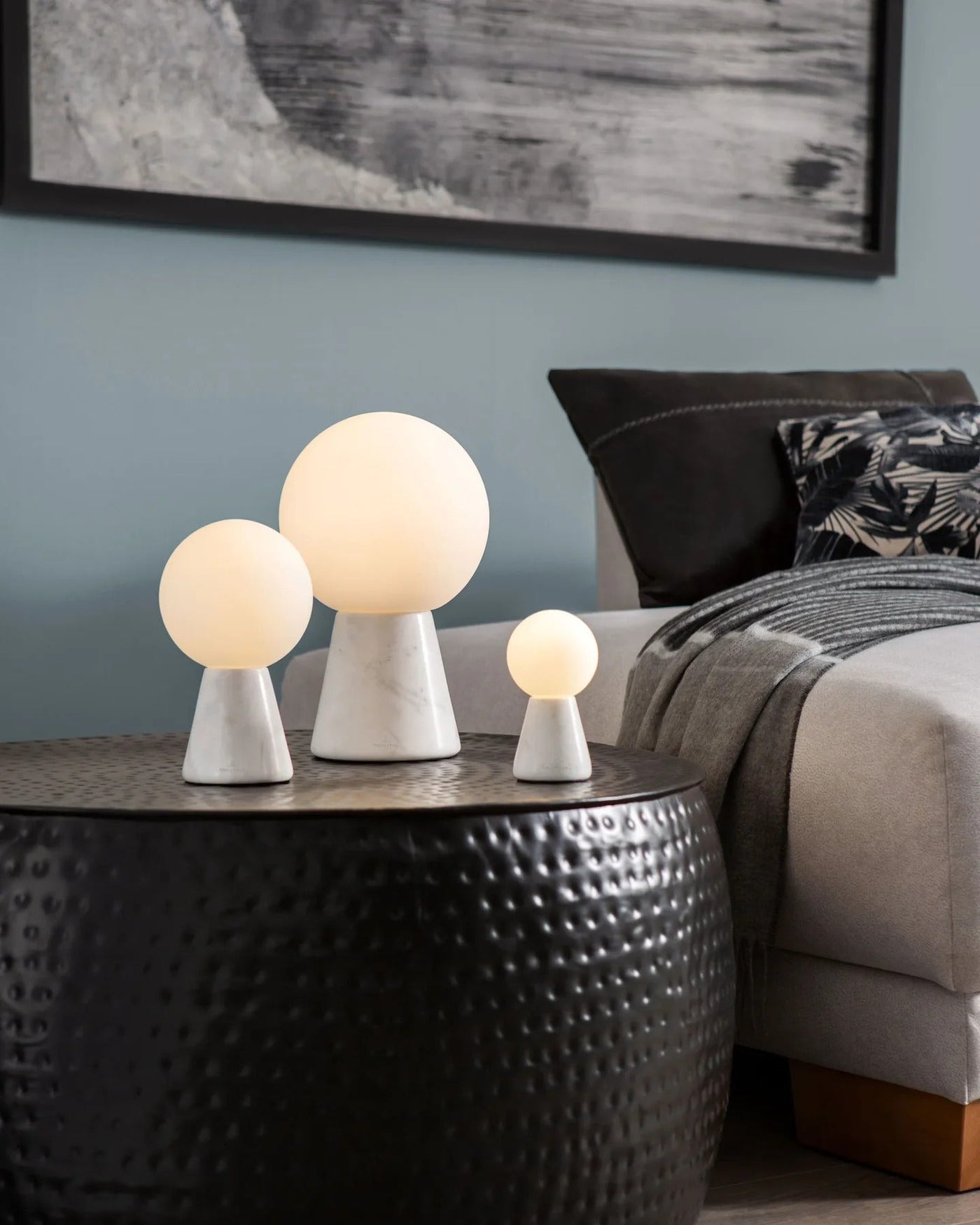 Bedroom lighting ideas using soft globe lights in varying sizes on a textured black bedside table.