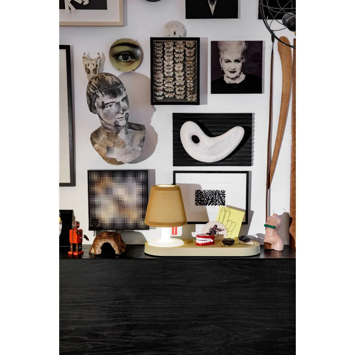 Fatboy Edison the Petit table lamp and styled on a vintage wood residence shelf with framed art in a cosy living room setup, from tableLights.com.