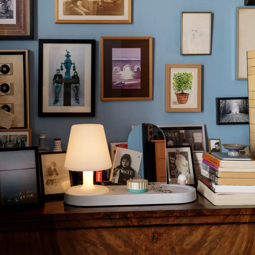 Fatboy Edison the Petit table lamp, styled on a vintage wood residence shelf with framed art in a cosy living room setup, from tableLights.com.