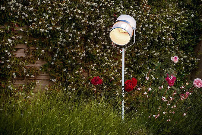 Maiori La Lampe Paris floor lamp solar light for home, placed in a garden setting among flowers and greenery.