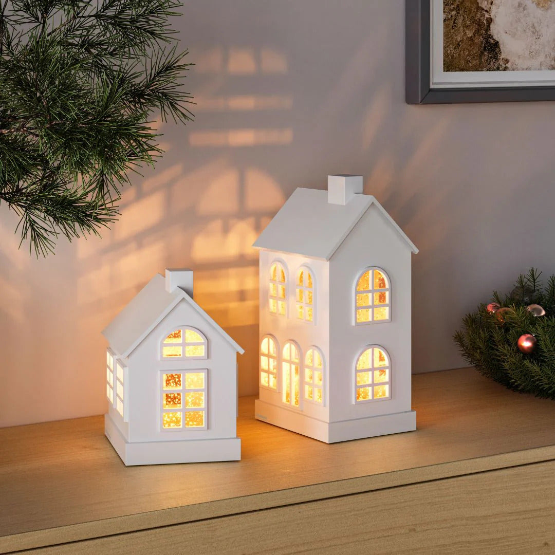 Sompex Glamor House Decorative Lamp White, offering a warm decorative light with internal glow, placed on a wooden sideboard with seasonal greenery.
