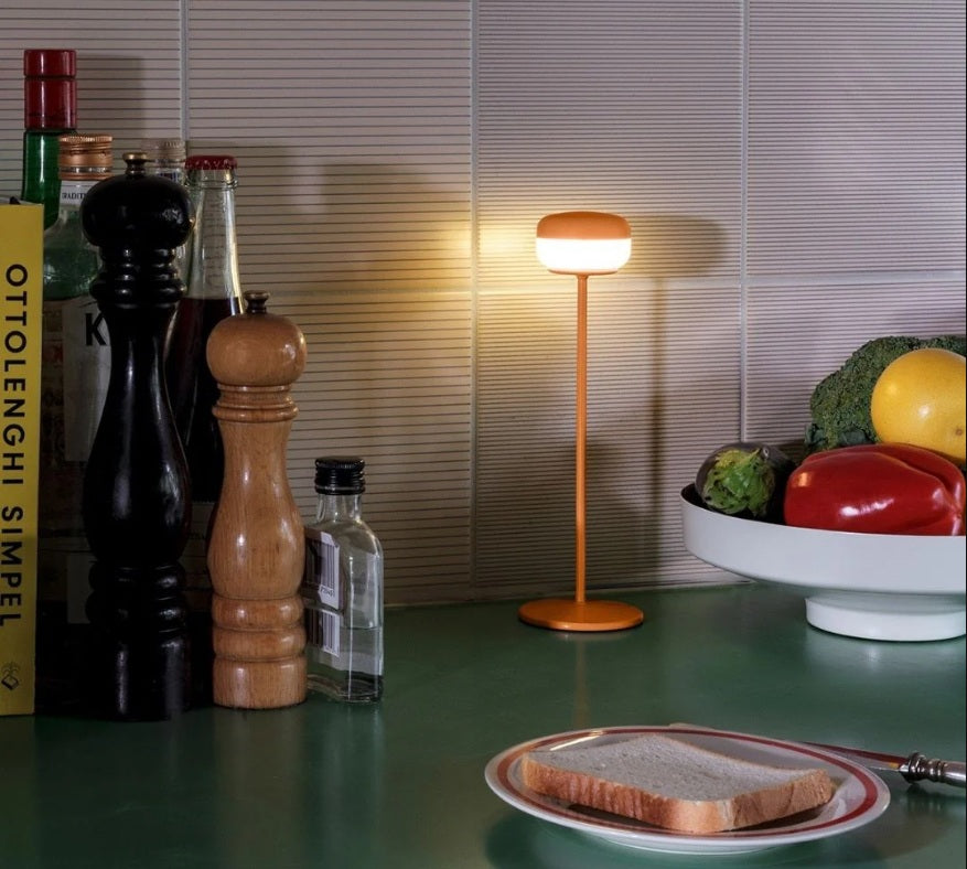 Warm ambient light from a Fatboy Cheerio lamp brightens a kitchen counter setup with fresh ingredients and cookbooks.